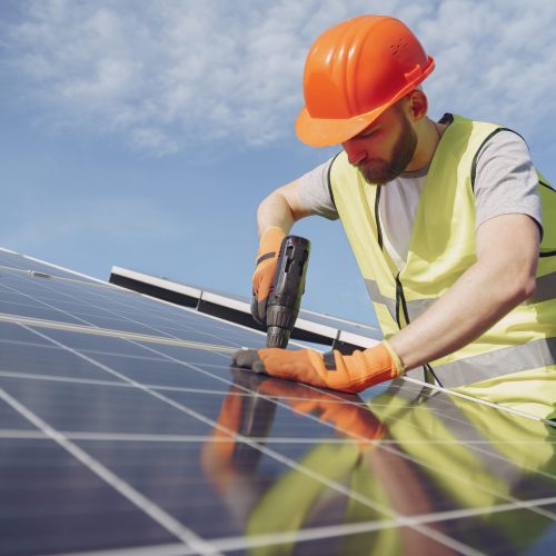 Male worker with solar batteries. Man in a protective helmet. Installing stand-alone solar panel system.